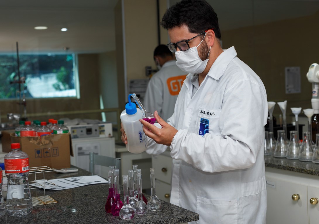 Analista da GTA preparando soluções em balões volumétricos no laboratório de físico-química